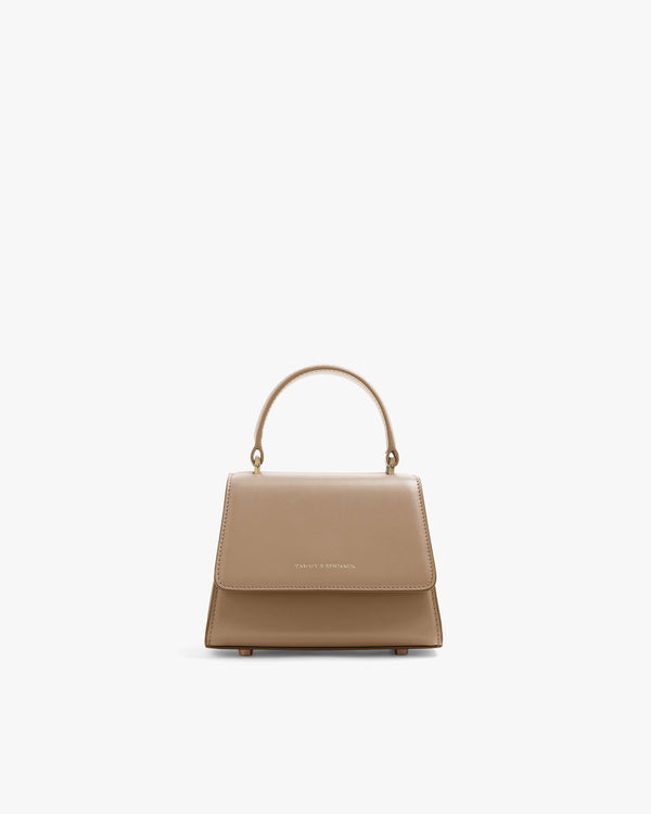 Sac ALEXIA NANO beige de face, rabat fermé, poignée rigide, posé sur fond blanc