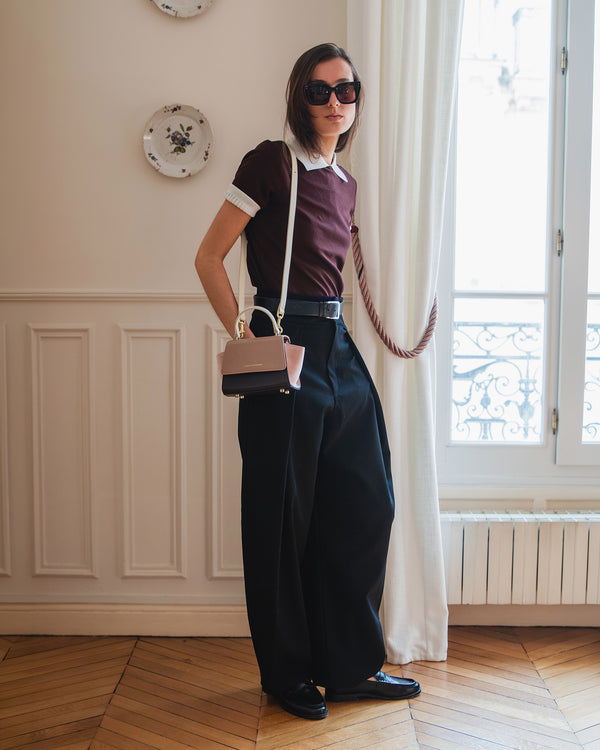 Sac ALEXIA NANO Colourblock Marlowe porté en bandoulière avec anse rigide, sur une tenue noire et bordeaux