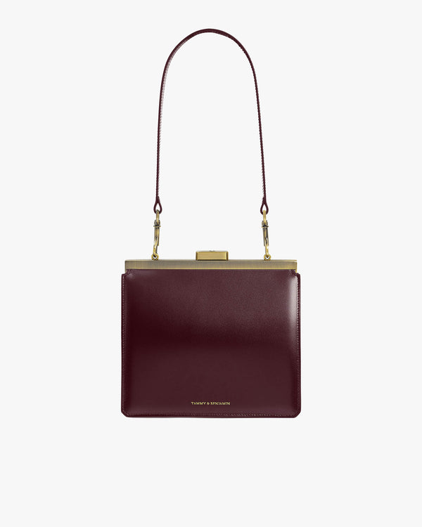 JEANNE bag in Mahogany, front view, gold-tone metal clasp, worn with long shoulder strap