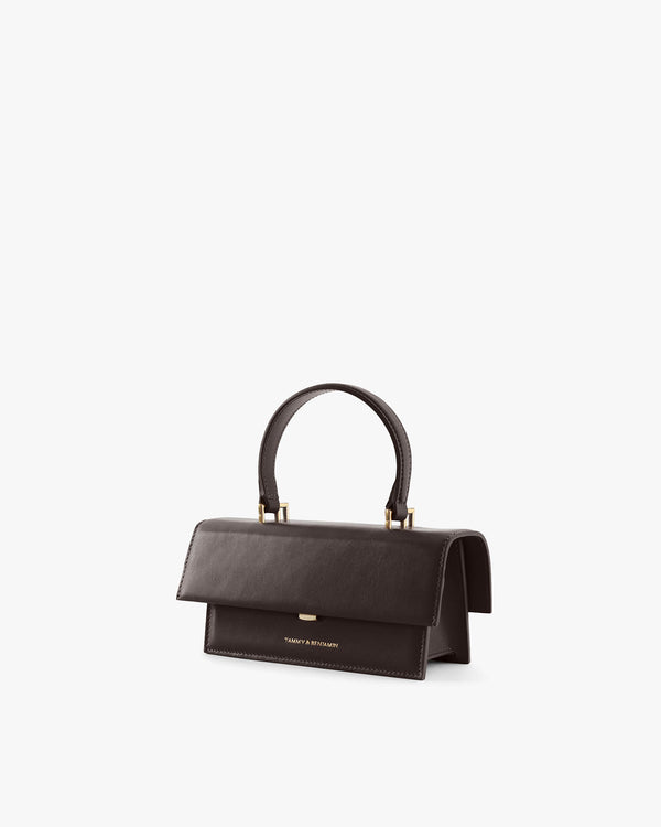 THEA MINI bag in chocolate, three-quarter view, flap closed, carried by top handle