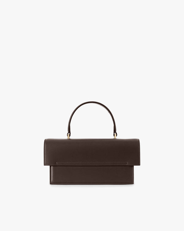 THEA bag in Chocolate, front view, flap closed, rigid handle standing upright