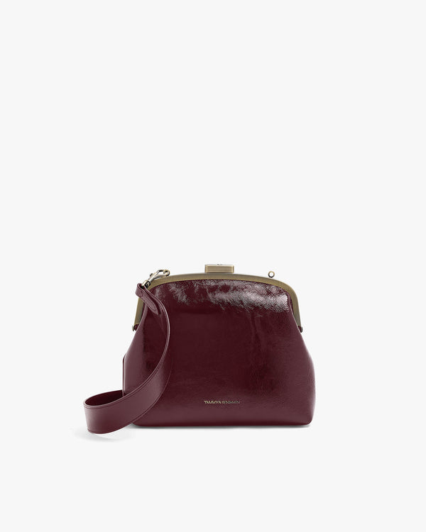 Sac EMMA bordeaux naplak de face, posé, avec bandoulière longue attachée et fermoir doré