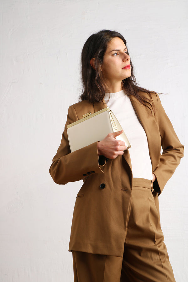 JEANNE bag in Ivory, held by hand, gold-tone clasp detail, worn at an angle